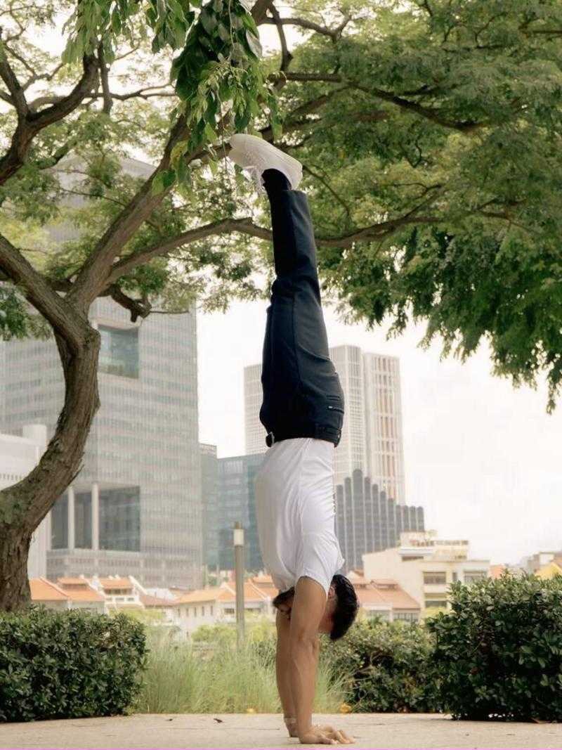Coach Alexander in a handstand under a tree in Singapore
