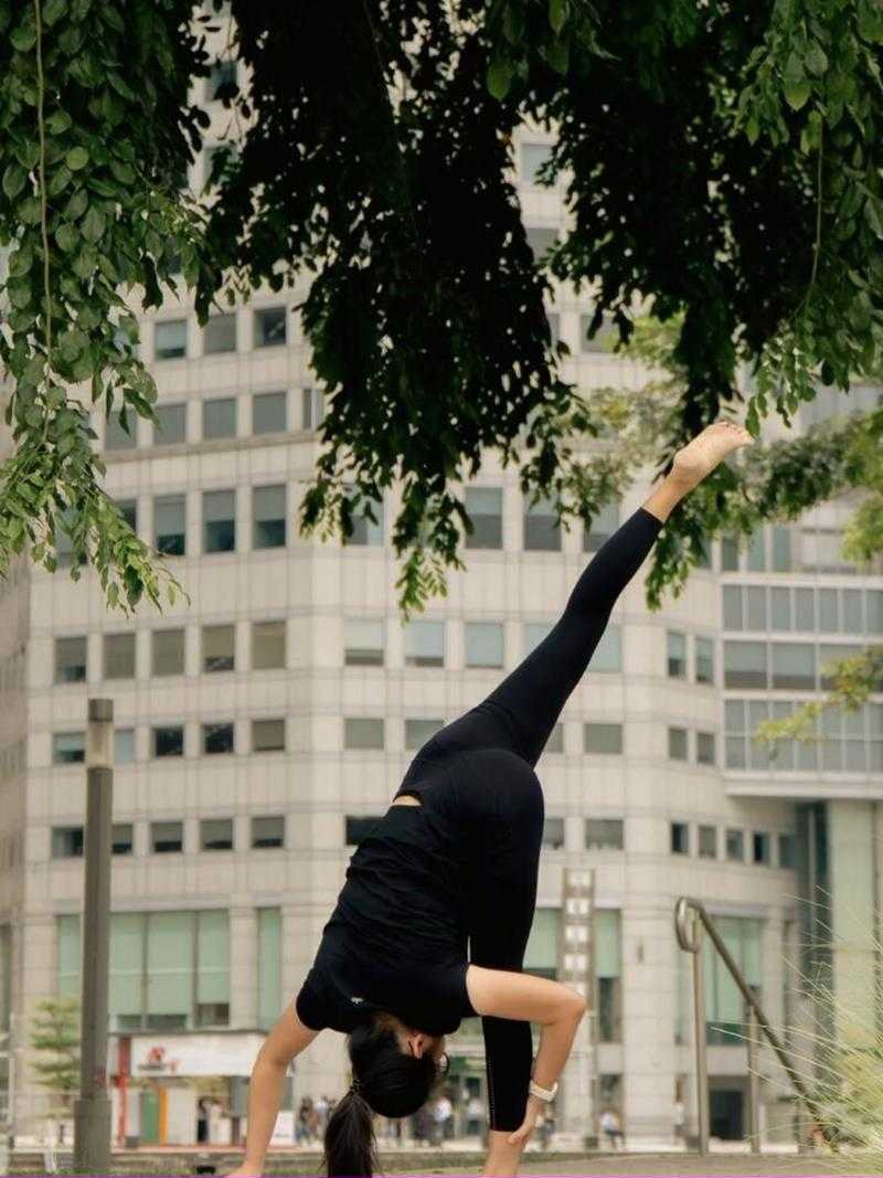 Coach Shu Ting in a standing split under a tree