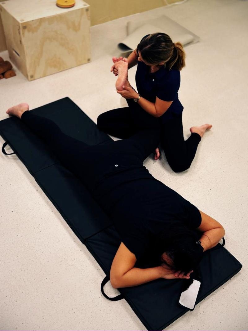 Coach working through hip and foot mobility with a client on the floor