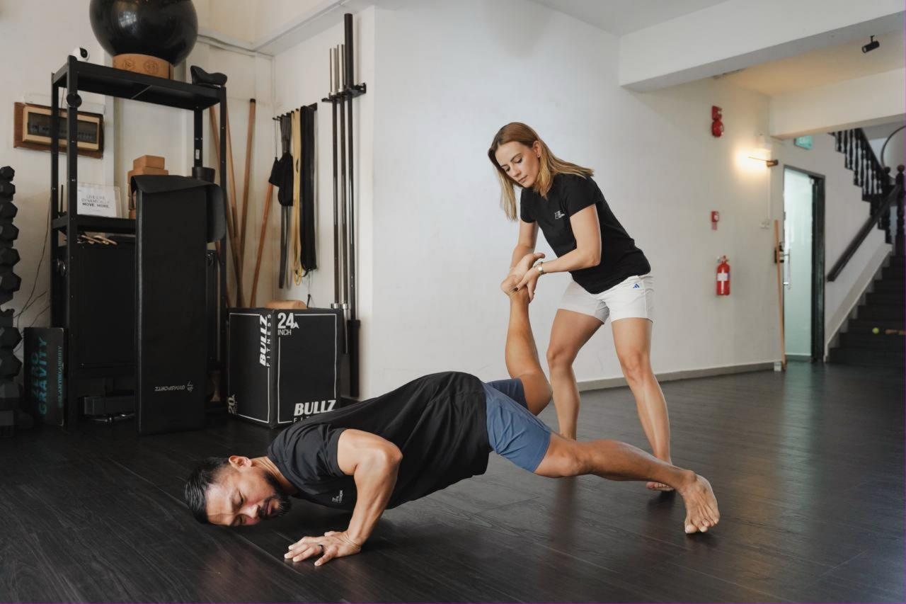 Coach Bronwen guiding a client through a floor movement at Uncommon Movement Studio